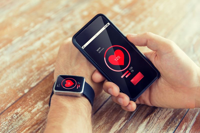 Wearables o que é: homem usando smartwatch e acompanhando seus batimentos no celular.