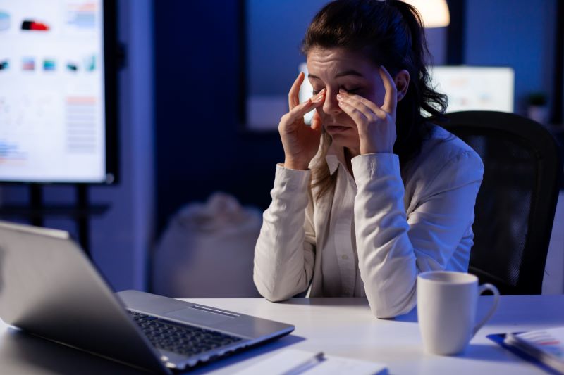 Vista cansada​: mulher esfregando os olhos enquanto trabalha no escritório