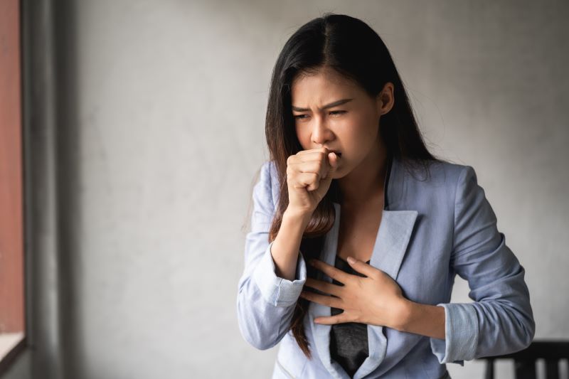 Enfisema pulmonar tem cura​: mulher tossindo com mão em frente à boca.