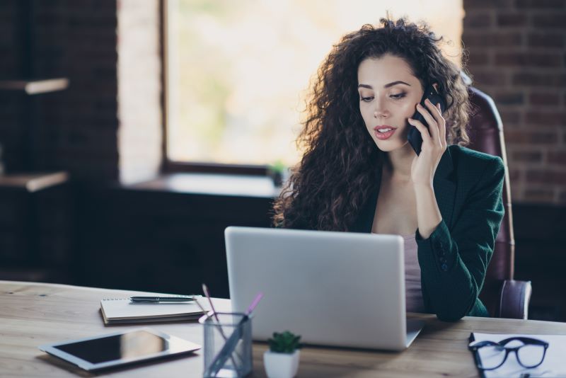 PPP e LTCAT: mulher no escritório falando ao celular e usando computador