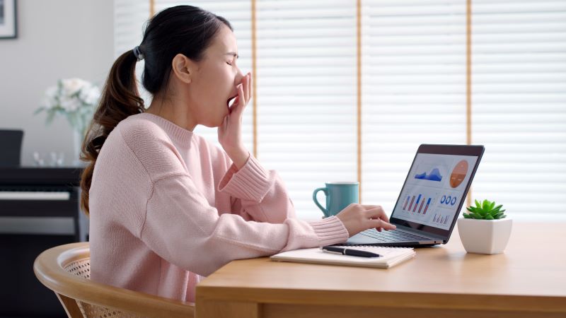 ergonomia cognitiva: mulher bocejando enquanto trabalha no computador