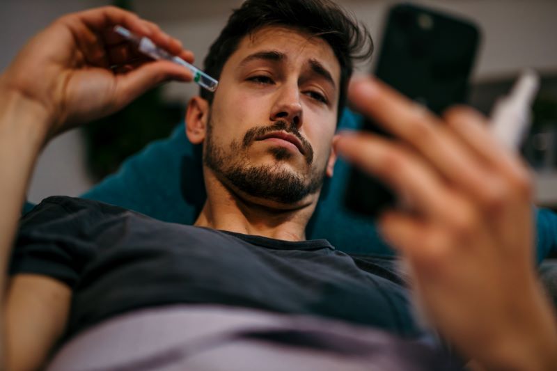 depois de quinze dias de atestado o que fazer​: homem doente em casa mexendo no celular