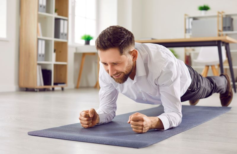ginástica laboral​: homem no trabalho fazendo abdominal prancha