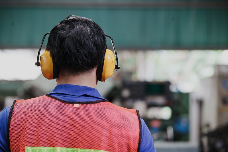 programa de conservação auditiva​: trabalhador de costas usando protetor auditivo