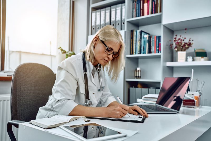 exame demissional quem paga: médica assinando exame em consultório